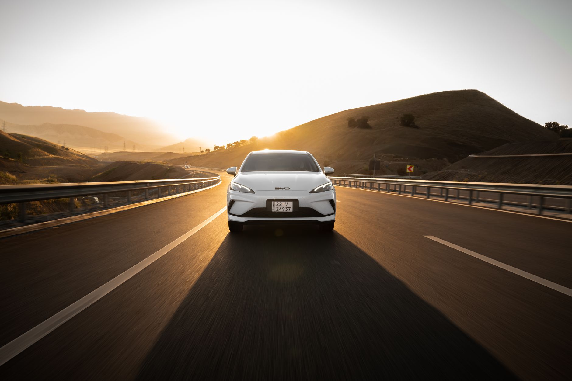 Electric car driving on a scenic highway at sunset, highlighting modern automotive design and sustainable travel.