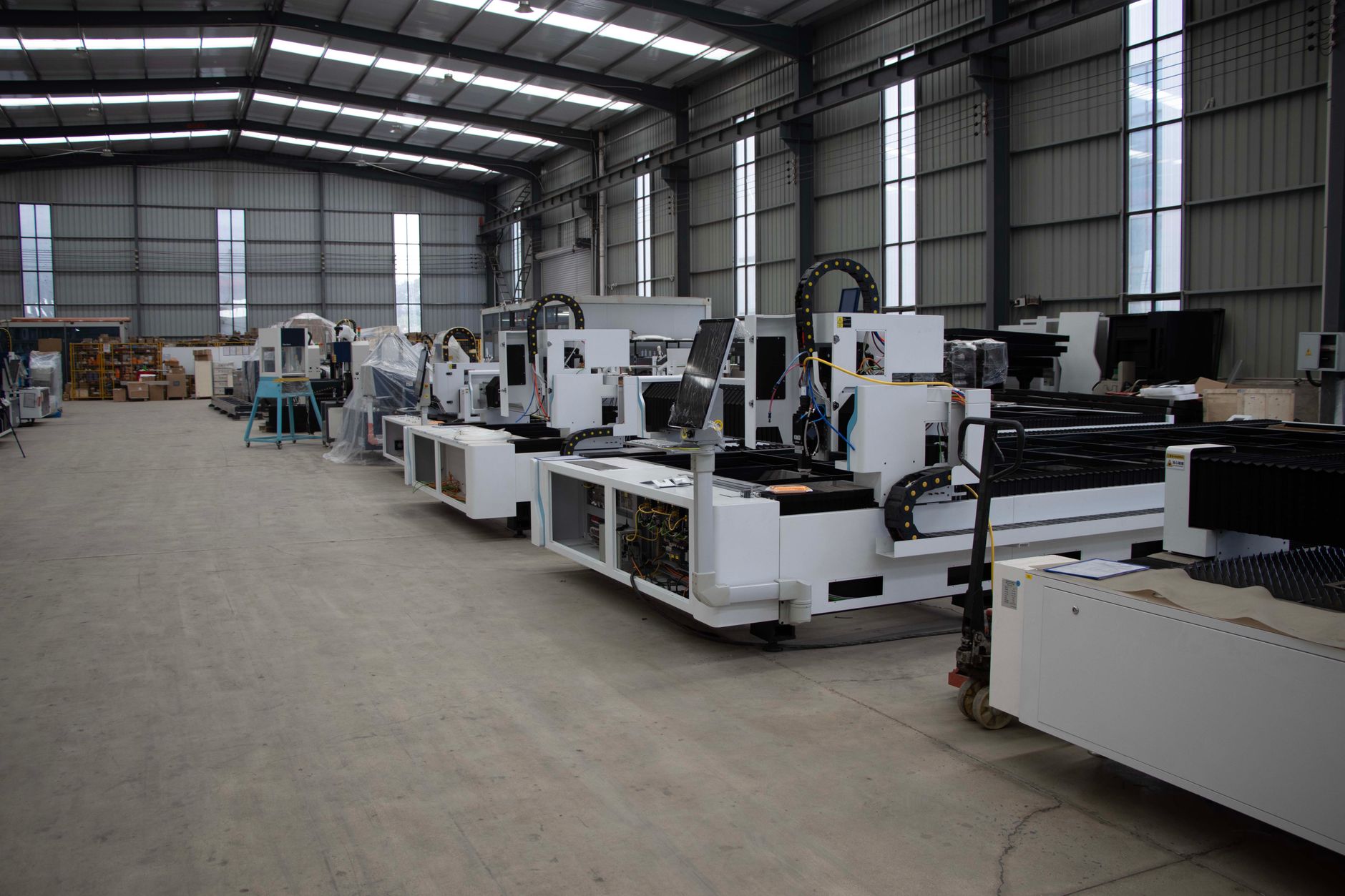 Row of advanced industrial manufacturing machines inside a spacious warehouse setting.