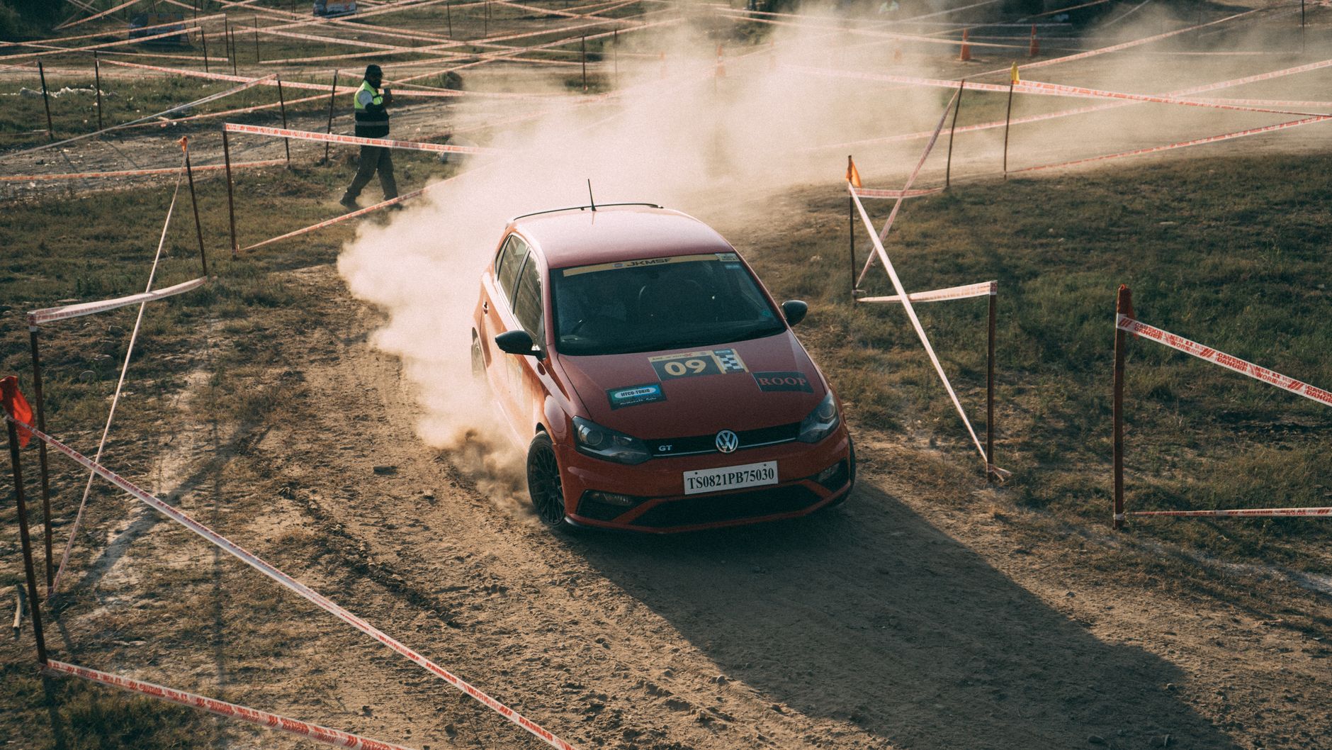 Red Volkswagen Polo GT racing on a dusty track, capturing high-speed action.
