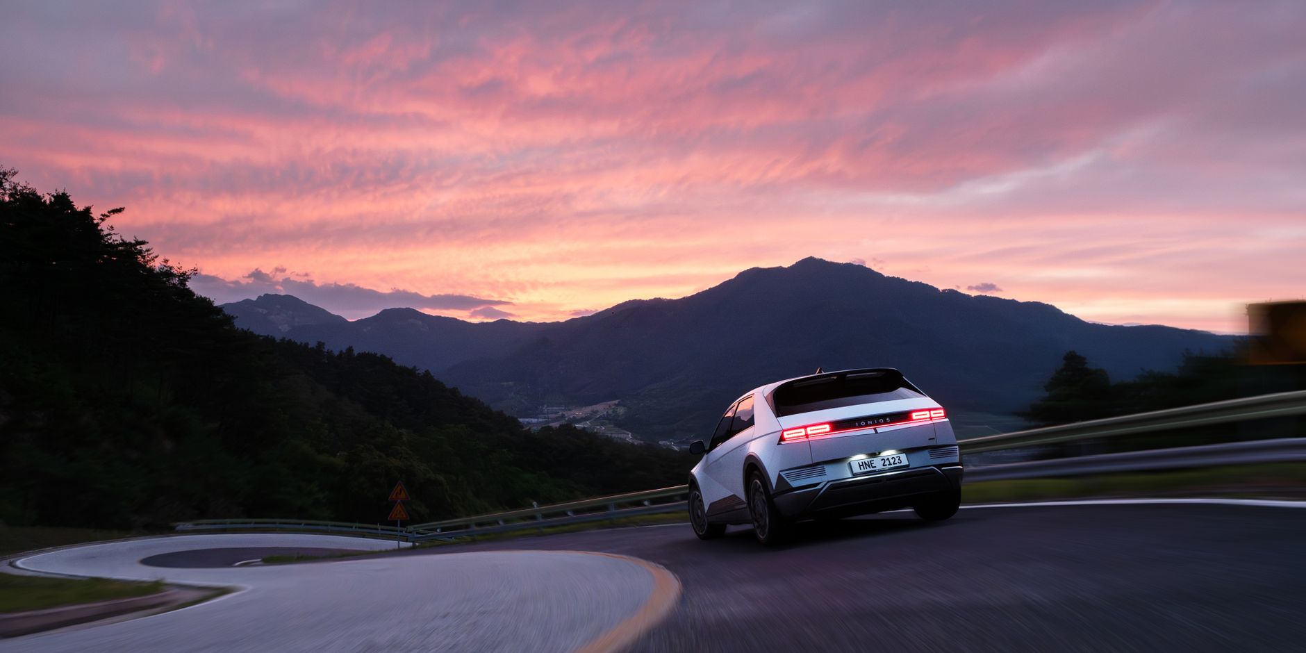 Hyundai Ioniq 5 on a mountain road during a stunning sunset, showcasing modern electric mobility.