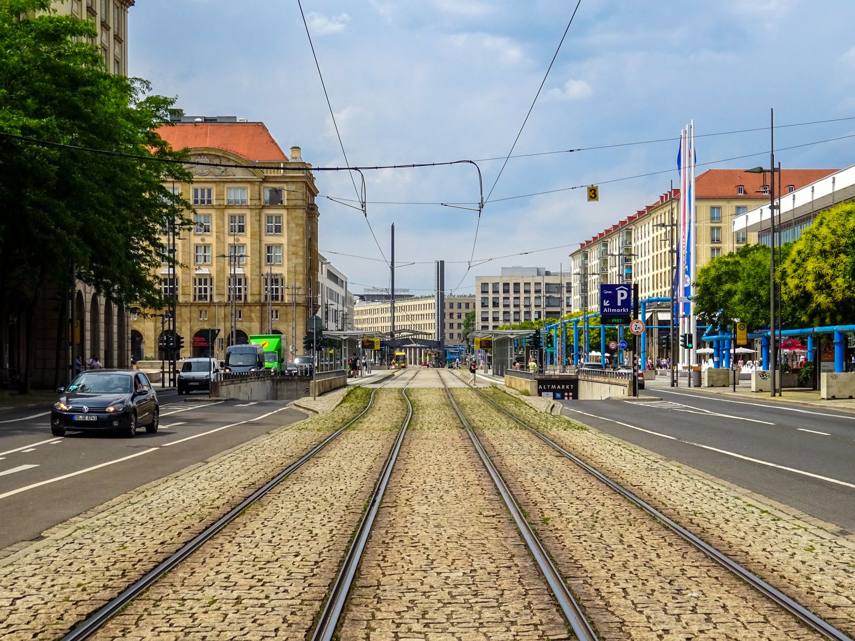 Cobblestone tram tracks through Dresden city with architecture and traffic.